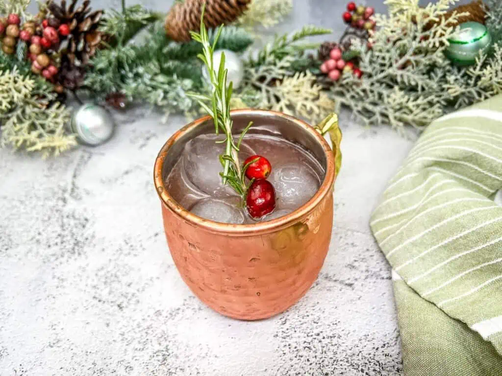 A mistletoe mule with cranberries and a sprig of rosemary.