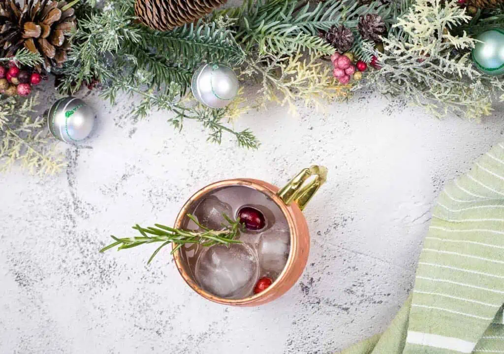 A copper mug surrounded by christmas decorations.