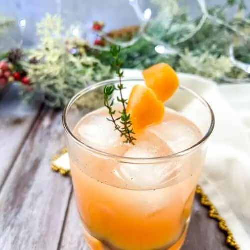 A Vanilla & Thyme Paloma garnished with sprigs of thyme.