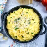 A bowl of polenta with mascarpone with tomatoes in the background.