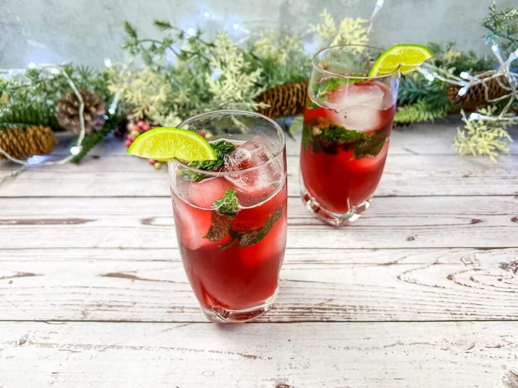 Two glasses of Pomegranate Mojitos on a wooden table.