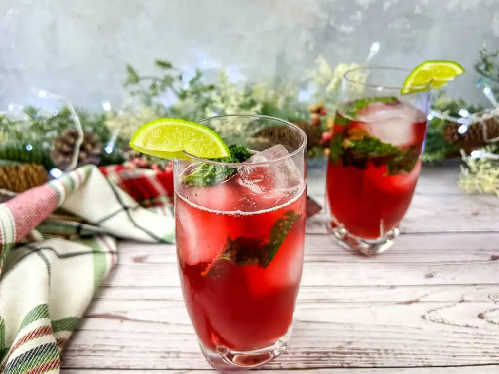 Two glasses of Pomegranate Mojitos on a wooden table.