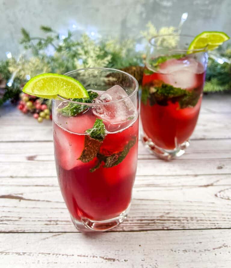 Two glasses of Pomegranate Mojitos with lime and mint.