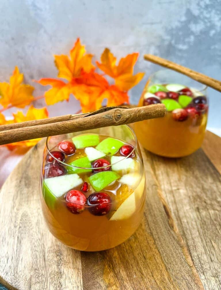 Two glasses of cranberry cranberry sangria with cinnamon sticks.