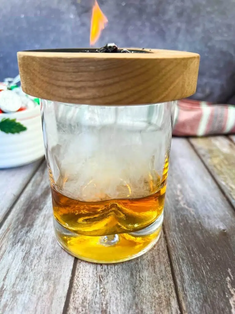 A glass of whiskey with a candle in it.