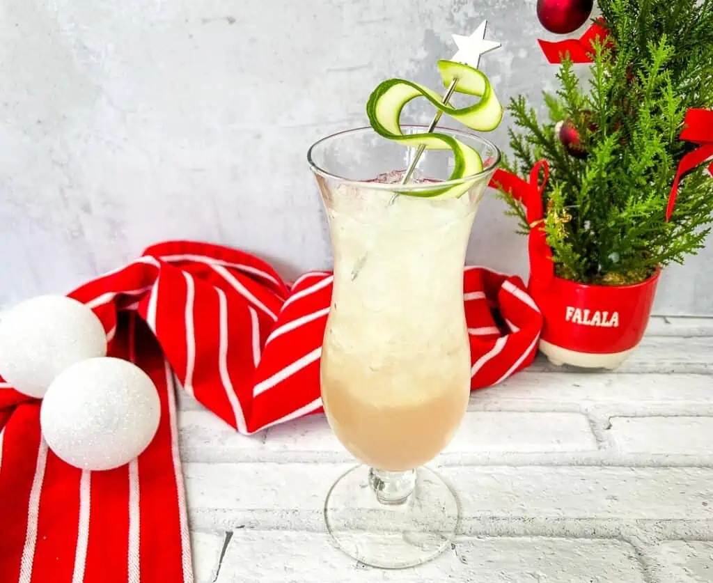 A cocktail with a lime garnish and a christmas tree.