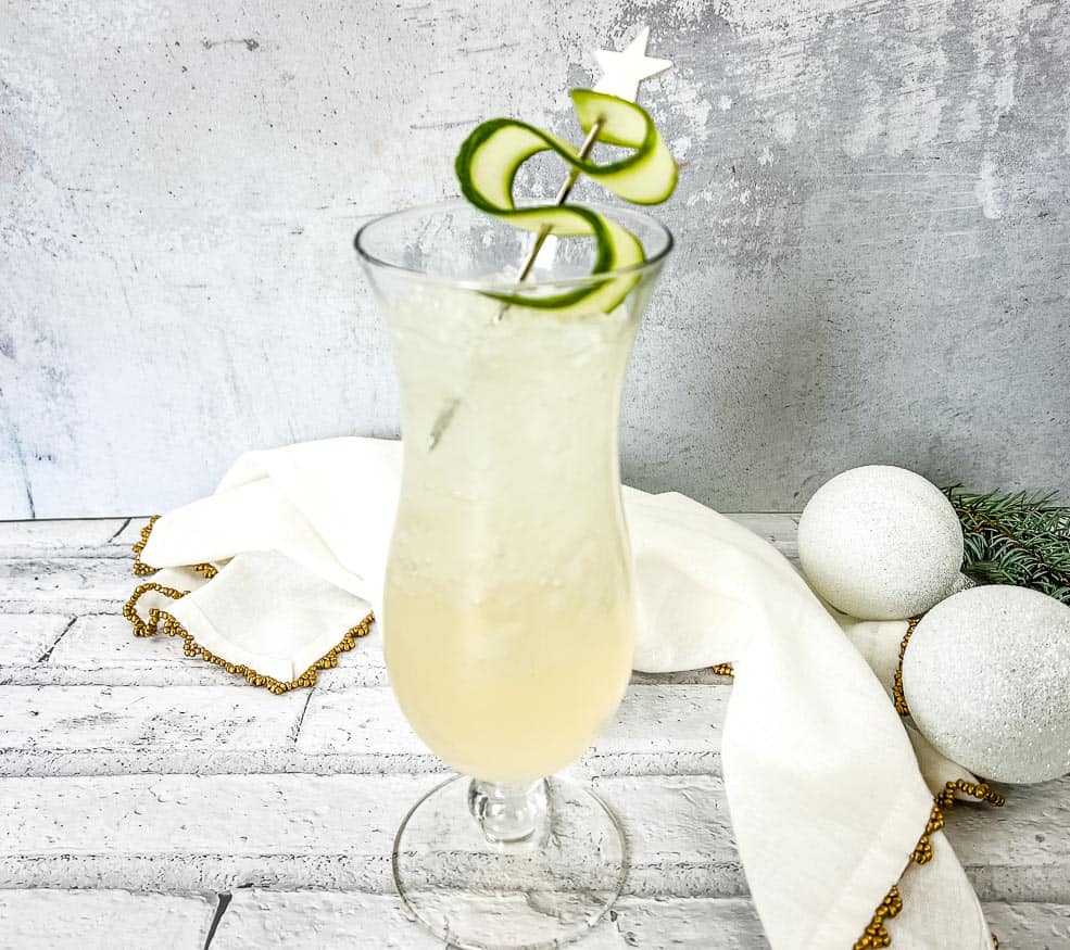 A cocktail with a cucumber garnish on top of a napkin.