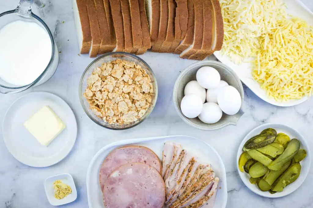 Ham, eggs, bread, pickles, and milk on a marble table.