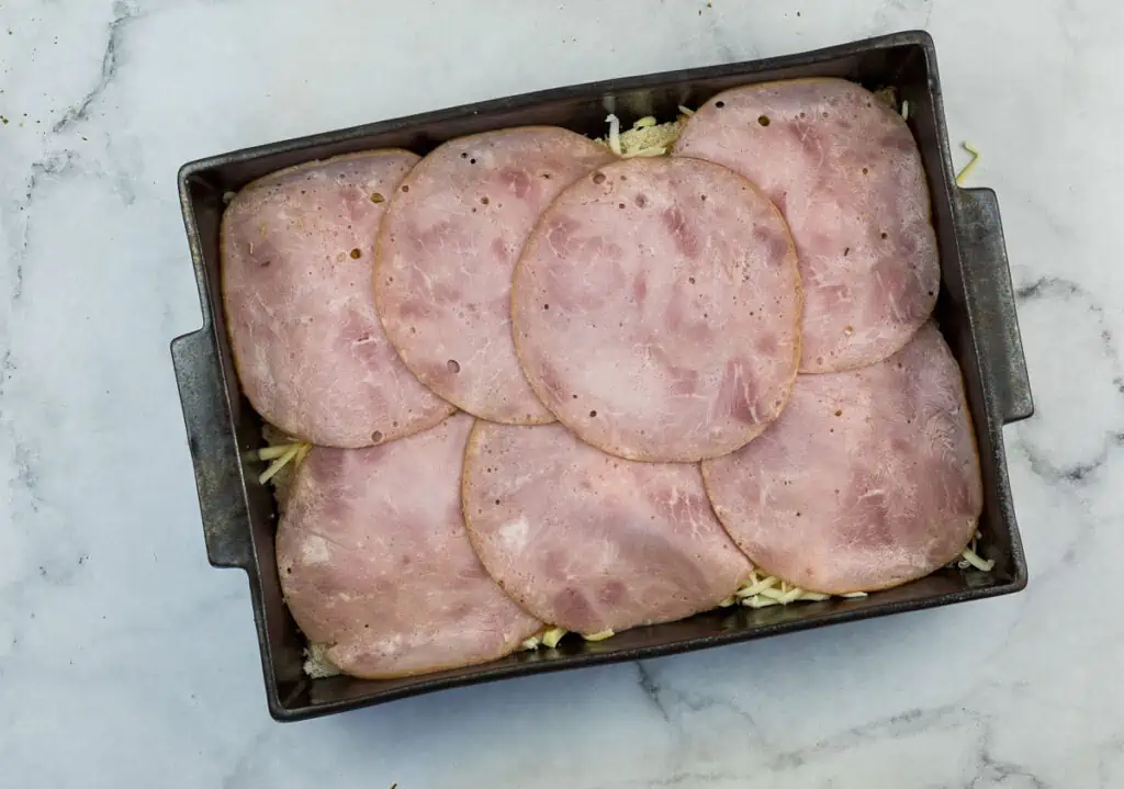 Sliced ham in a pan on a marble countertop.