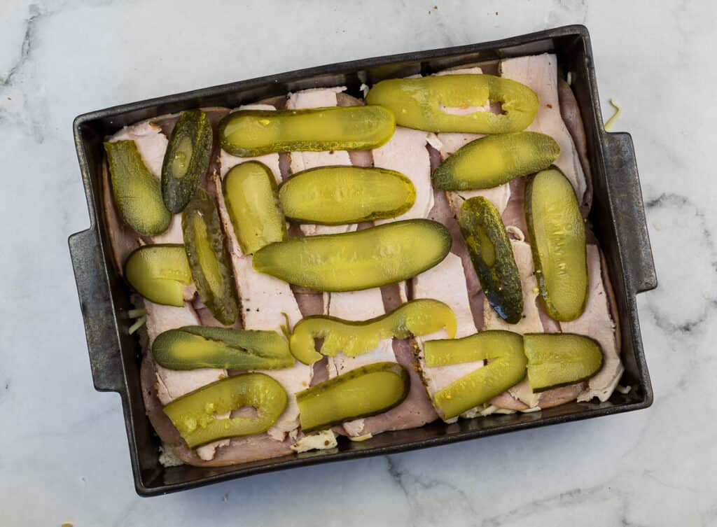 Ham and pickles in a baking pan.
