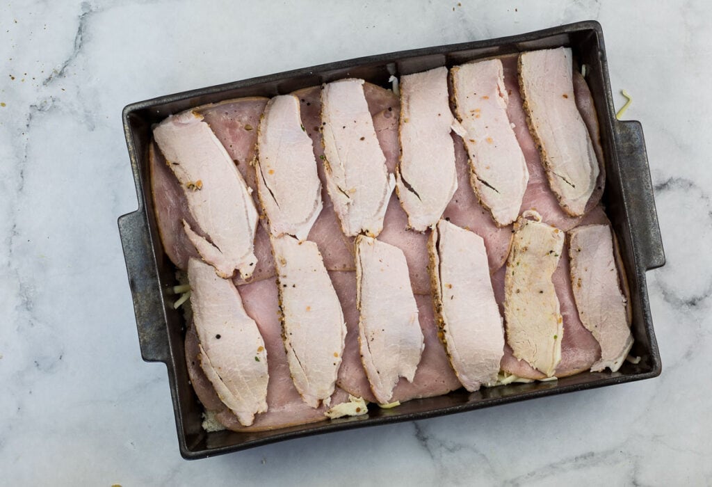 Sliced pork in a pan on a marble countertop.
