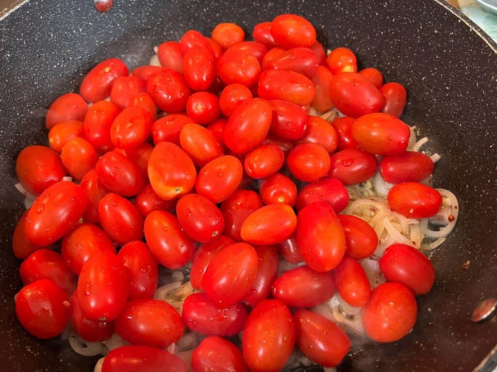 A frying pan filled with tomatoes and onions.