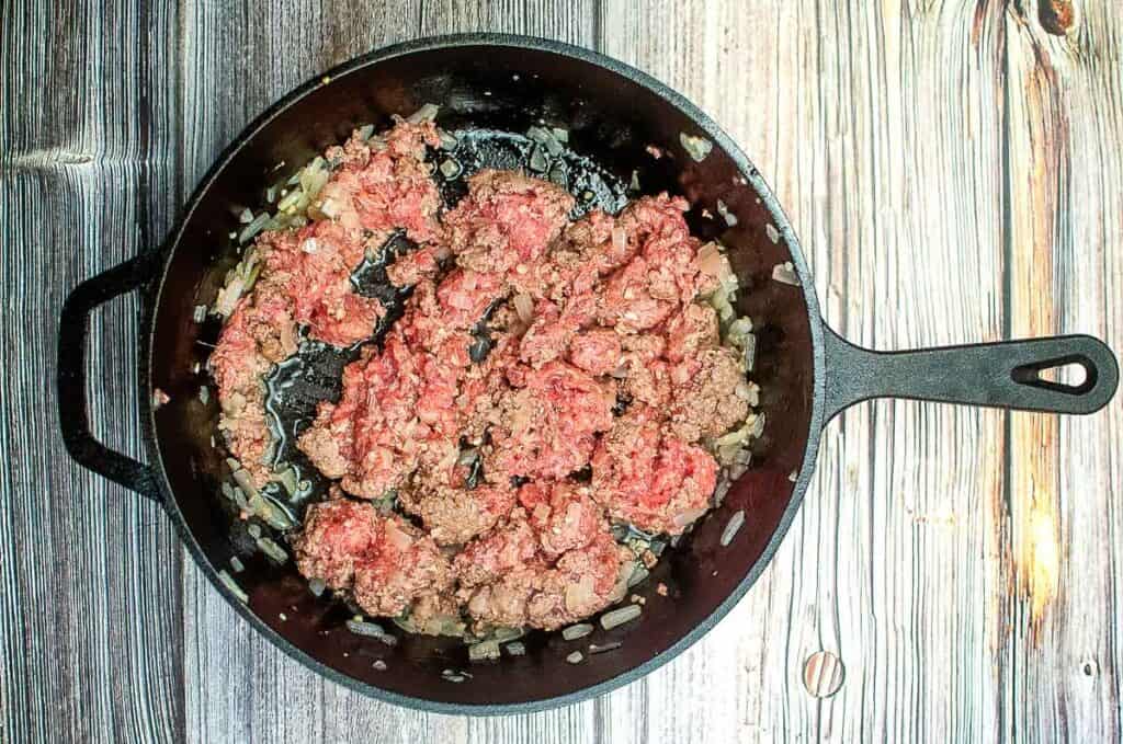 Ground beef in a skillet on a wooden table.