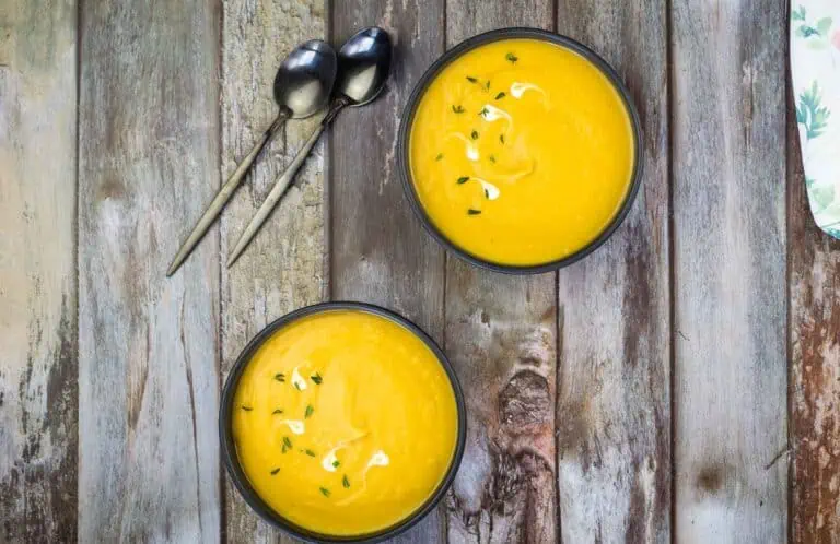 Two bowls of soup on a wooden table.