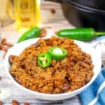 A bowl of chili with beans and jalapenos.