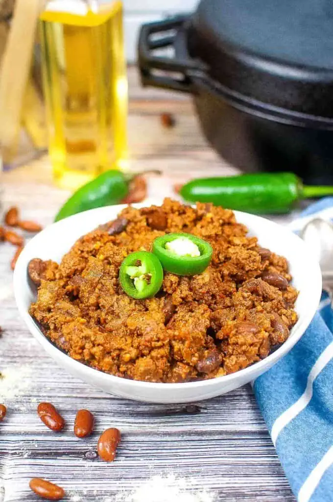 A bowl of chili with beans and jalapenos.