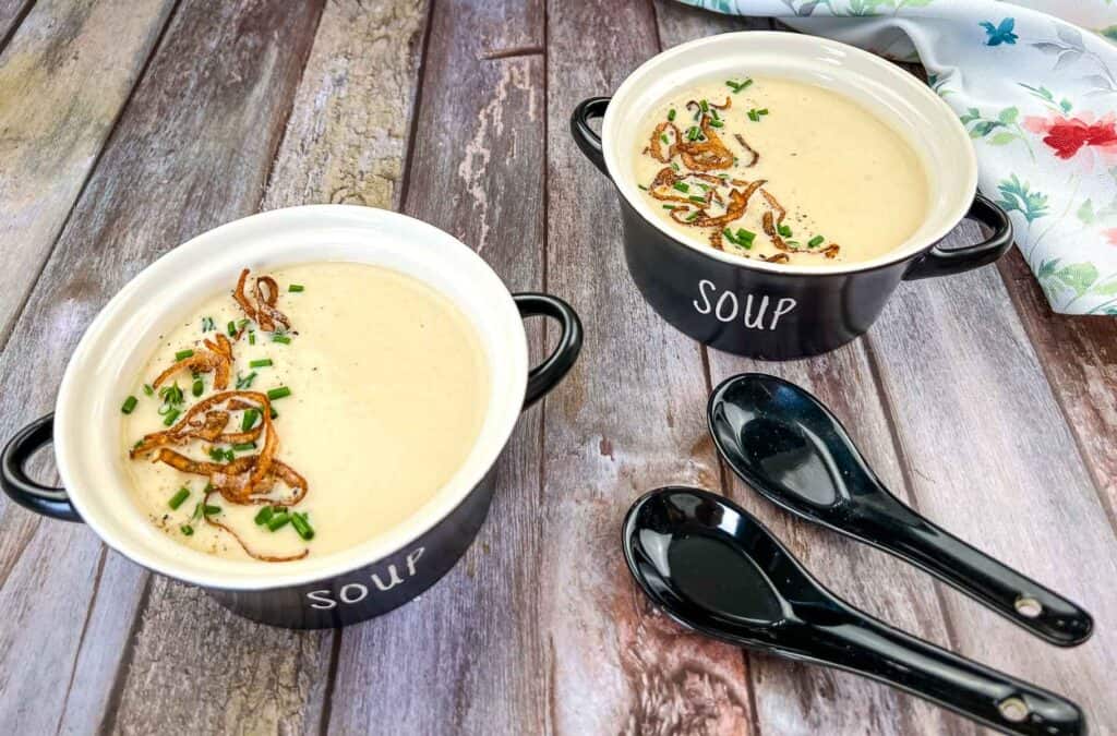 Two bowls of soup on a wooden table.