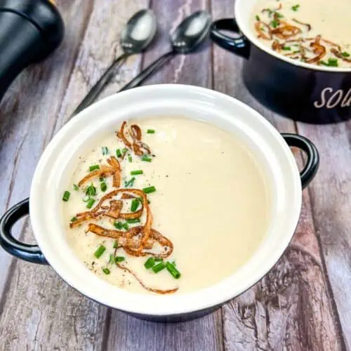 Two bowls of Cream of Onion Soup on a wooden table.