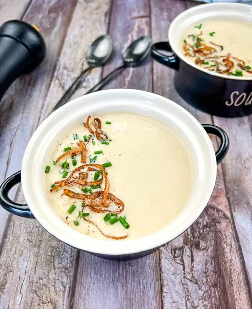 Two bowls of Cream of Onion Soup on a wooden table.