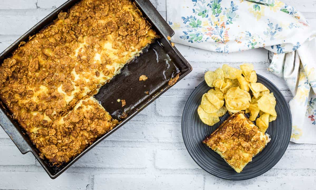 A piece of Cuban sandwich casserole on a plate with potato chips.