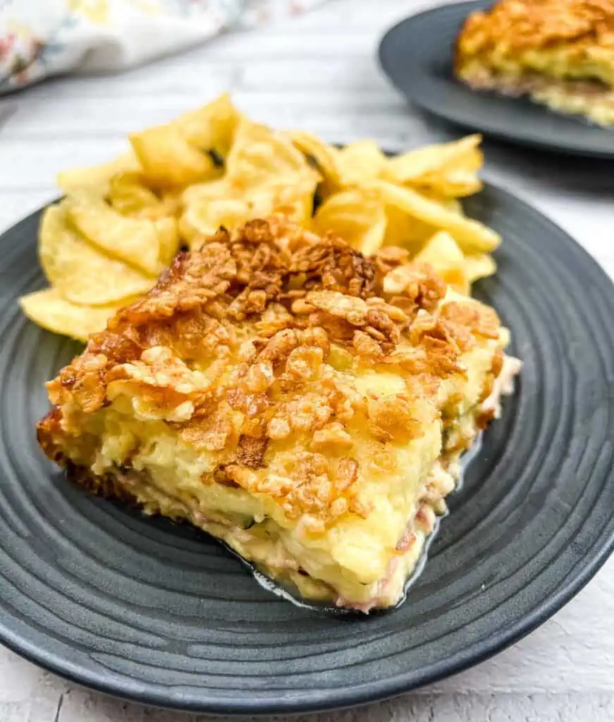 A slice of Cubano Sandwich Casserole on a plate with potato chips.