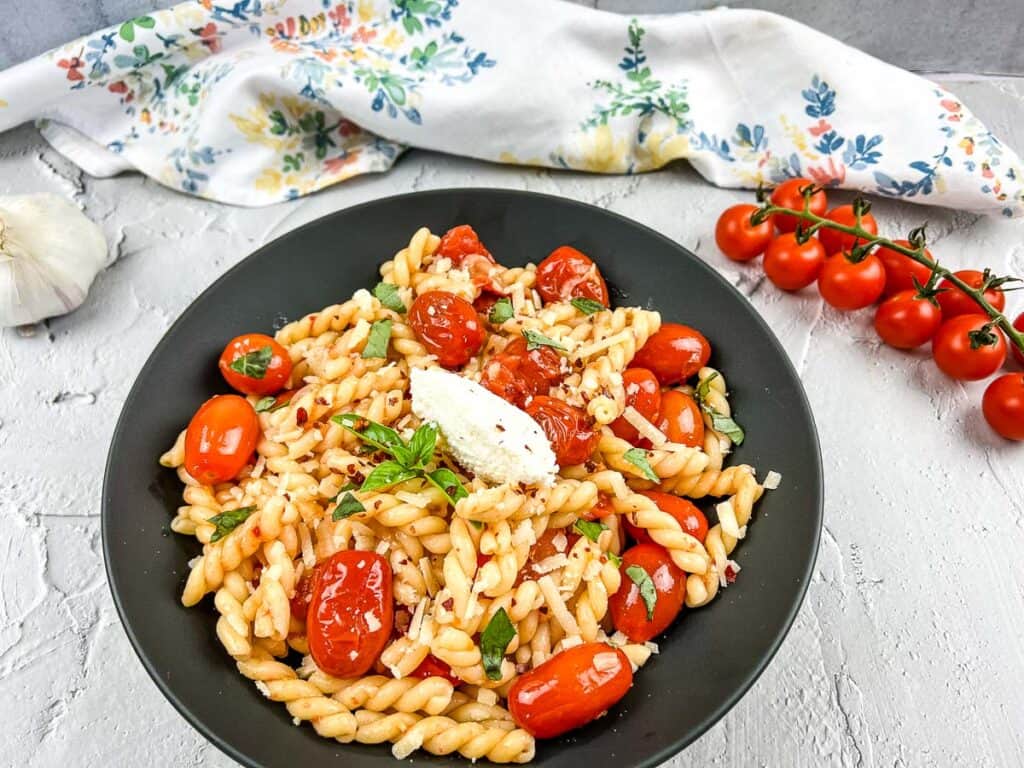 A bowl of pasta with tomatoes and garlic.
