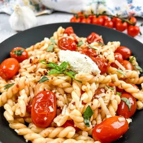 A plate of pasta with tomatoes and basil.