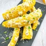 Corn ribs with parmesan and parsley on a black plate.