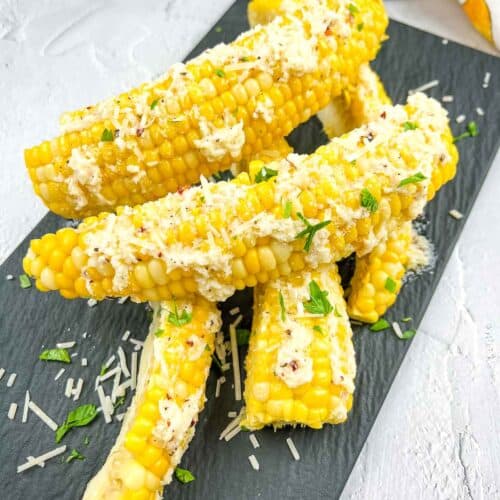 Corn ribs with parmesan and parsley on a black plate.