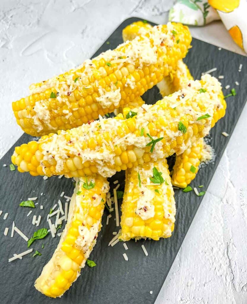 Corn ribs with parmesan and parsley on a black plate.