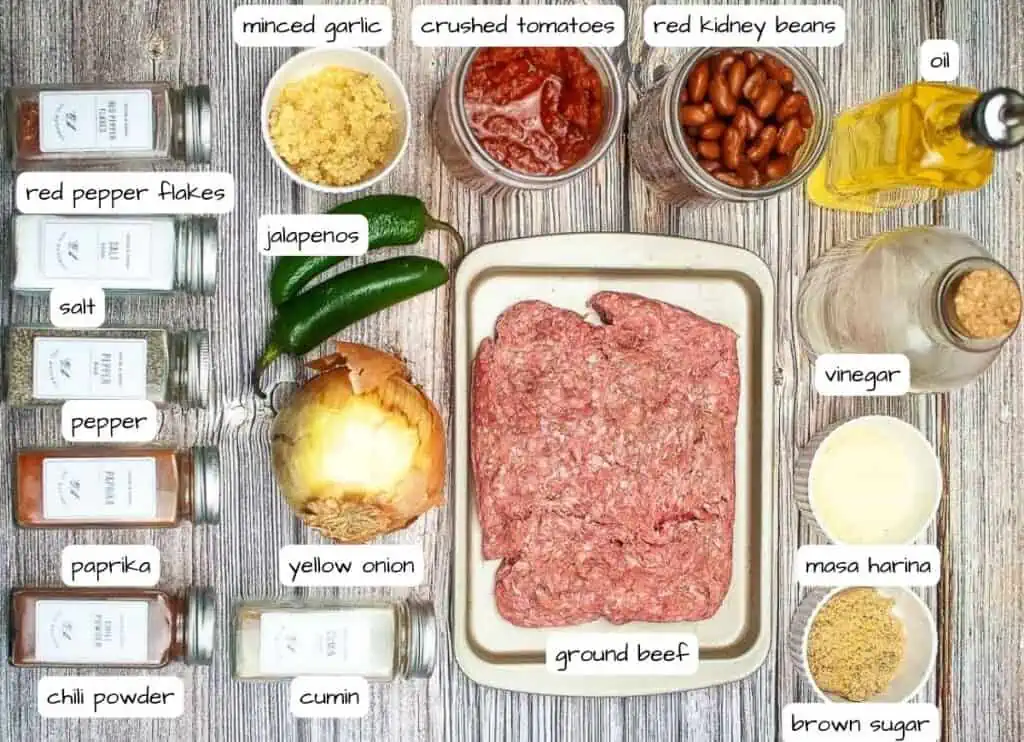 The ingredients for a beef burger are laid out on a wooden table.