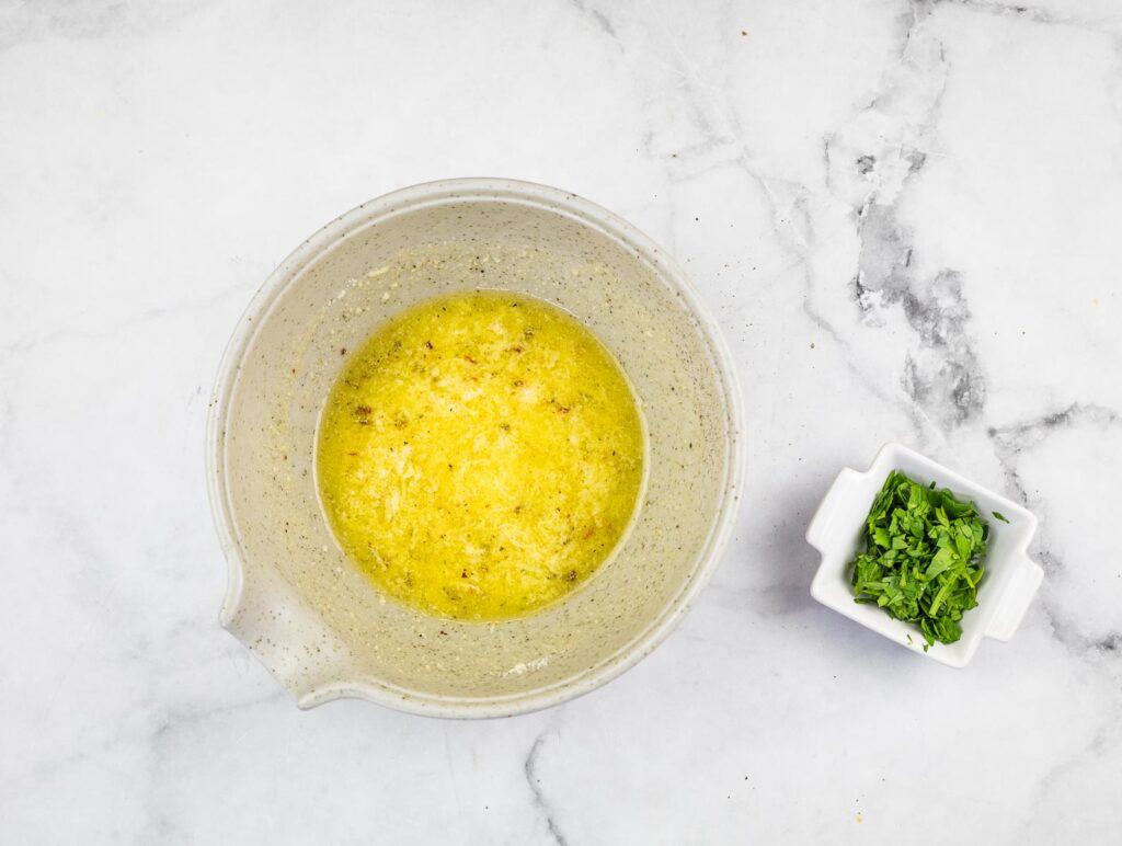 A bowl with lemon juice and parsley next to it.