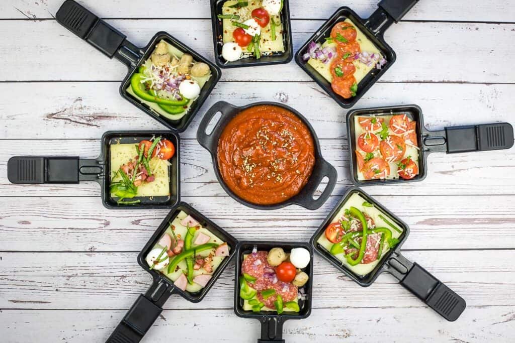 A group of black trays filled with food and sauce.