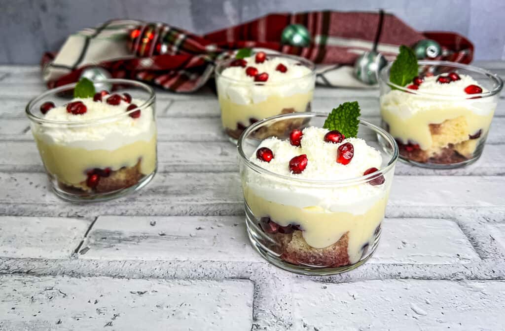 Four glasses with whipped cream and pomegranate on top.