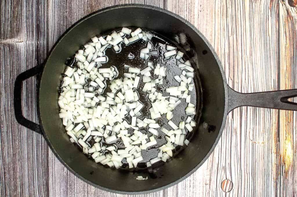A frying pan filled with onions on a wooden table.