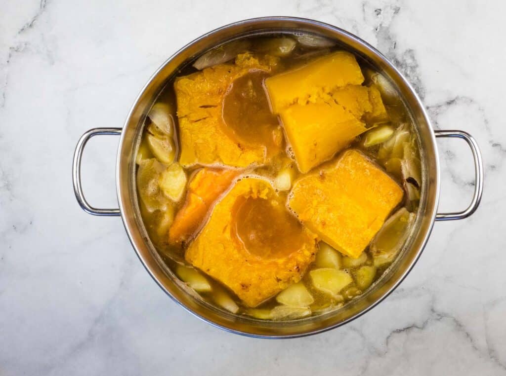 A pot of soup with carrots and potatoes in it.