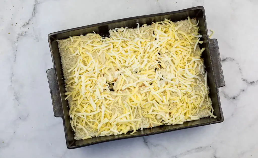Cheese on top of bread slices in a baking dish.