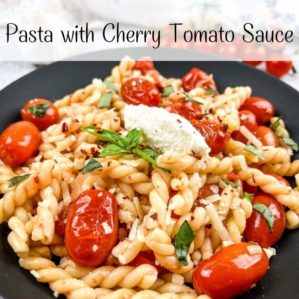 Pasta with cherry tomato sauce on a black plate.