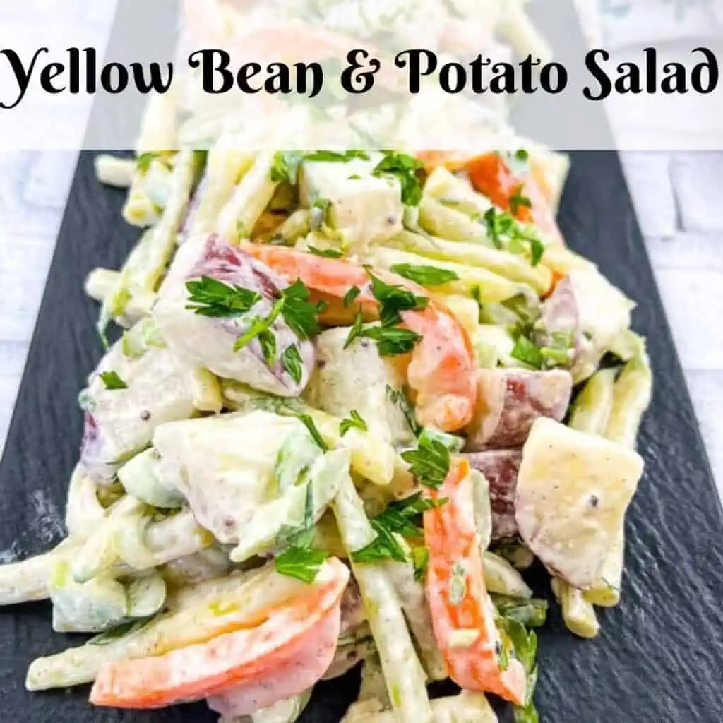 Yellow bean and potato salad on a black plate.