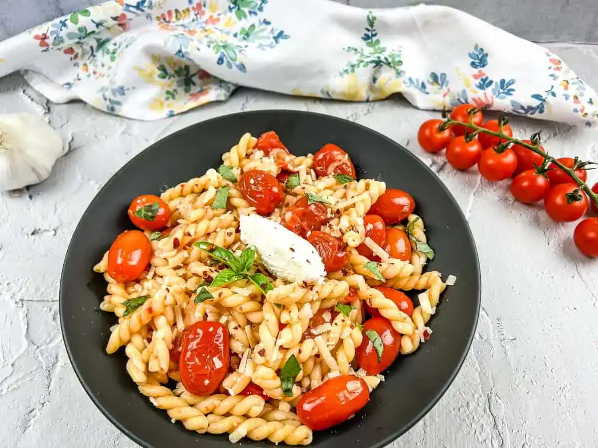 A plate of pasta with cherry tomatoes.