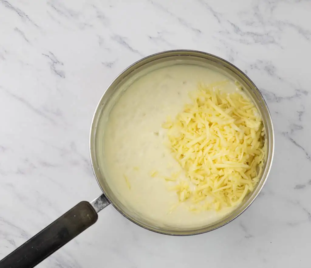 A pot with cheese in it on a marble countertop.