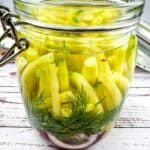 Dill pickles in a glass jar on a wooden table.