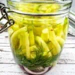 Dill pickles in a glass jar on a wooden table.