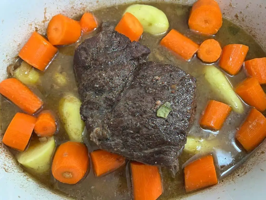 Beef stew with carrots and potatoes in a white bowl.