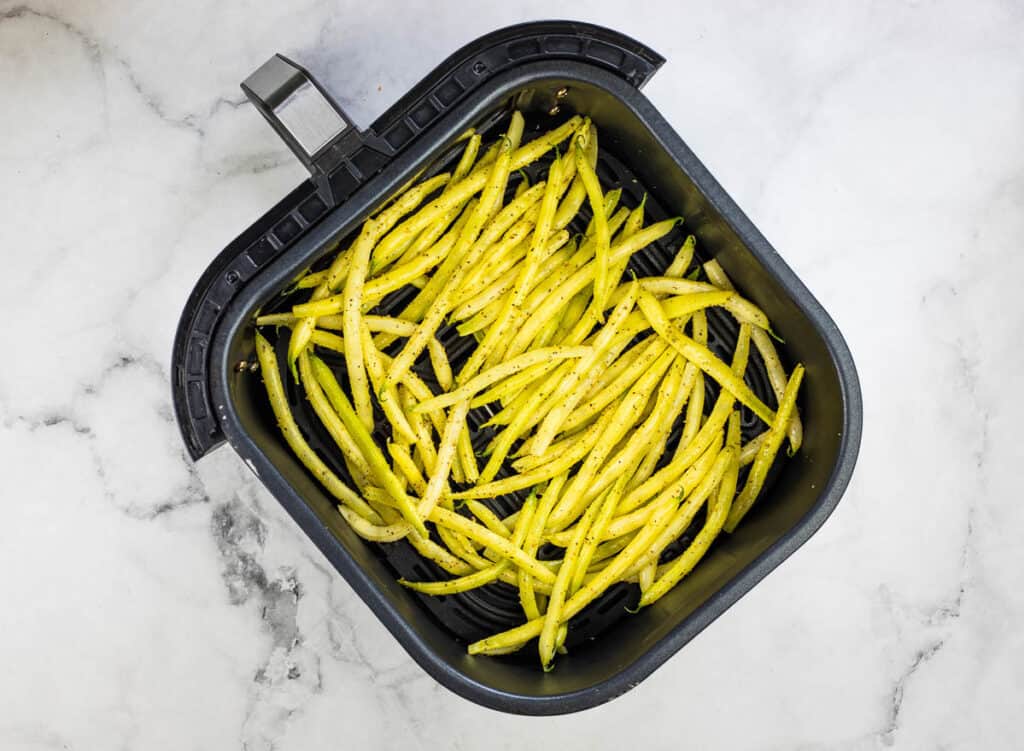 An air fryer filled with green beans.