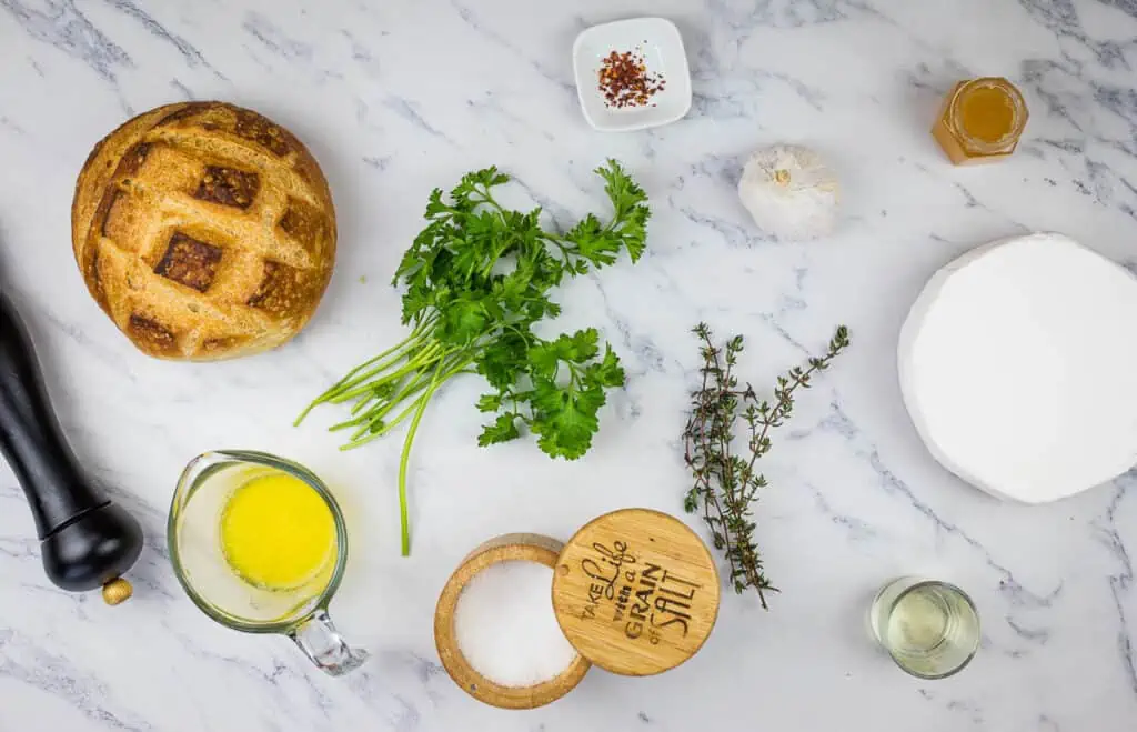 The ingredients for a bread with herbs and spices on a marble table.