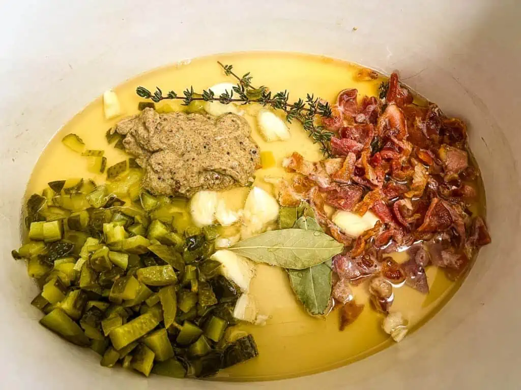 A slow cooker insert filled with bacon, celery, and other ingredients.