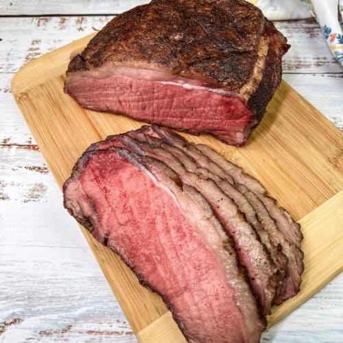Sliced Smoked New York Strip Roast on a cutting board.