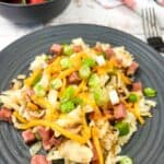 A plate with Montreal Smoked Meat Hash with strawberries in the background.