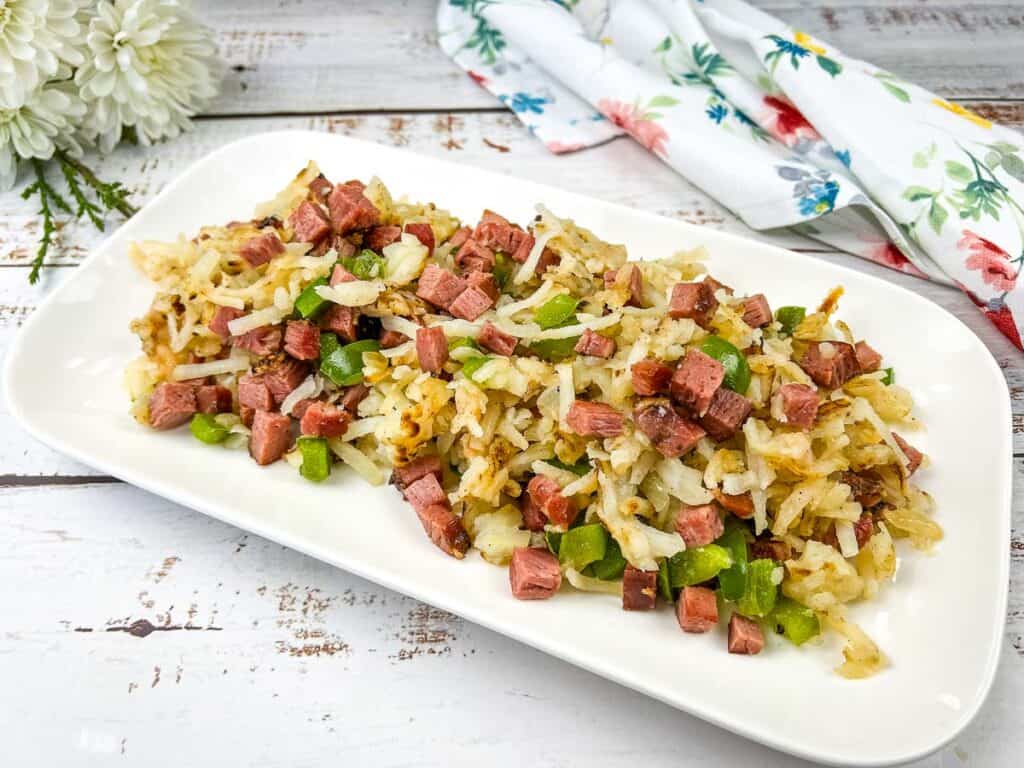 A white plate with breakfast hash on it.